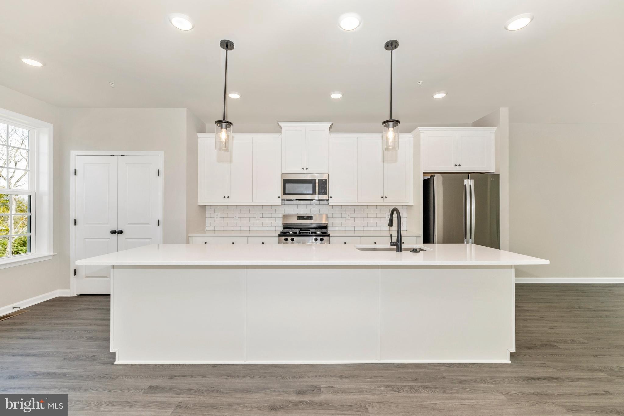 101 Spring Bank Way Frederick, MD 21701 - Photo 8 of 20 a large kitchen with kitchen island a stove a sink a center island and wooden floor