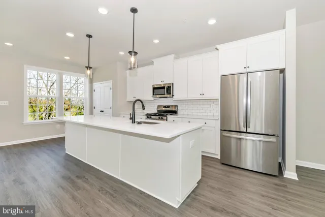 a kitchen with stainless steel appliances granite countertop a refrigerator a stove a sink and a microwave