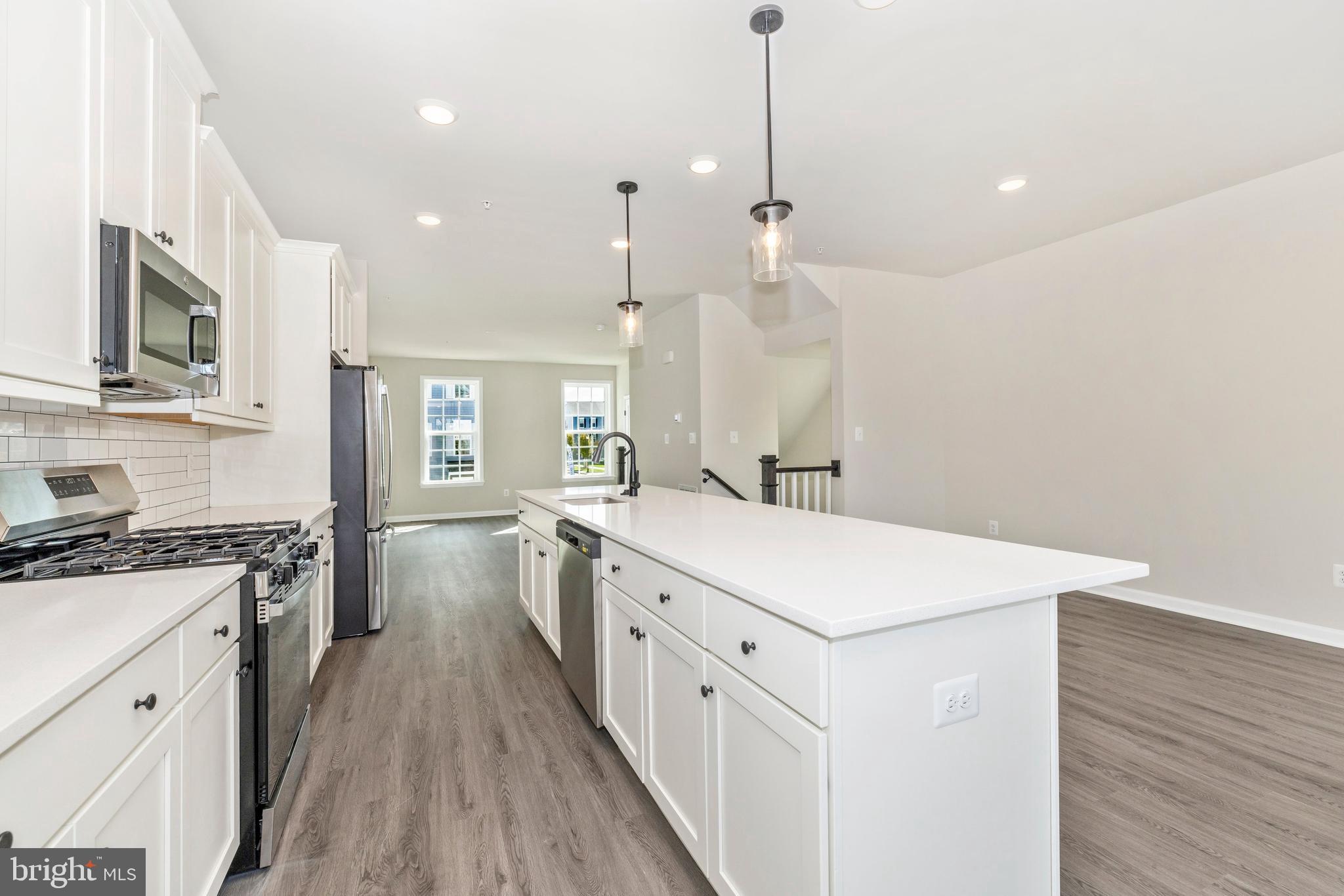 101 Spring Bank Way Frederick, MD 21701 - Photo 10 of 20 a large white kitchen with a stove a sink dishwasher and a refrigerator with wooden floor