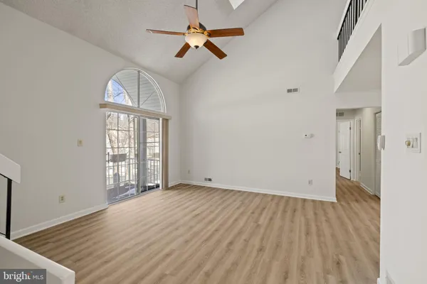 an empty room with wooden floor fan and windows