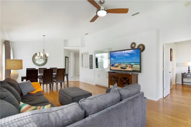 a living room with furniture kitchen view and a wooden floor