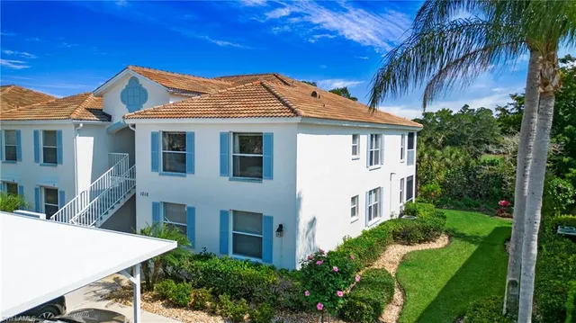 a view of a white house with a big yard and potted plants