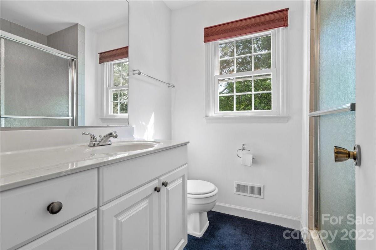 12112 Painted Tree Road Charlotte, NC 28226 - Photo 24 of 41 a bathroom with a granite countertop sink toilet a large mirror a shower and a window