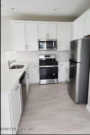 a kitchen with a sink a stove a refrigerator a microwave and cabinets