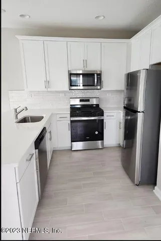 a kitchen with a sink a stove a refrigerator a microwave and cabinets