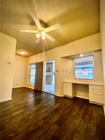a view of an empty room with window and wooden floor