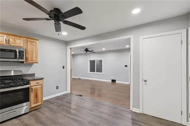 a view of a kitchen with a stove a microwave and a ceiling fan