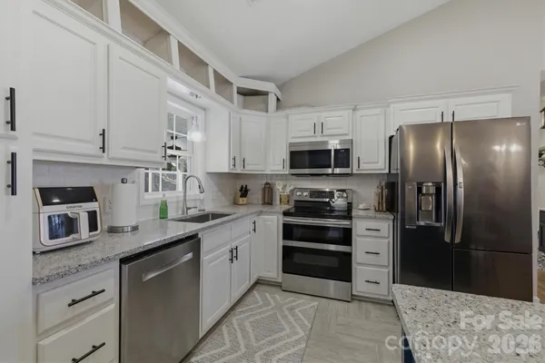 a kitchen with stainless steel appliances kitchen island granite countertop a refrigerator stove and sink
