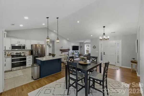 a kitchen with stainless steel appliances kitchen island granite countertop a table chairs and a refrigerator