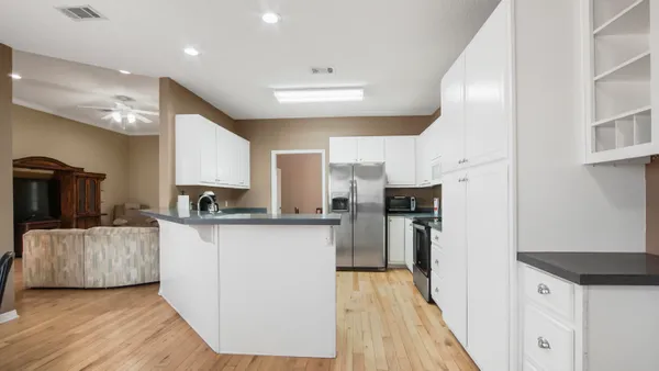 a kitchen with stainless steel appliances kitchen island granite countertop a refrigerator a stove and a wooden floors