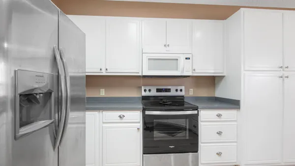 a kitchen with granite countertop white cabinets and stainless steel appliances