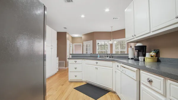 a kitchen with stainless steel appliances granite countertop a sink and white cabinets with wooden floor
