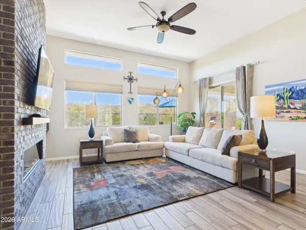 a living room with furniture large windows and wooden floor