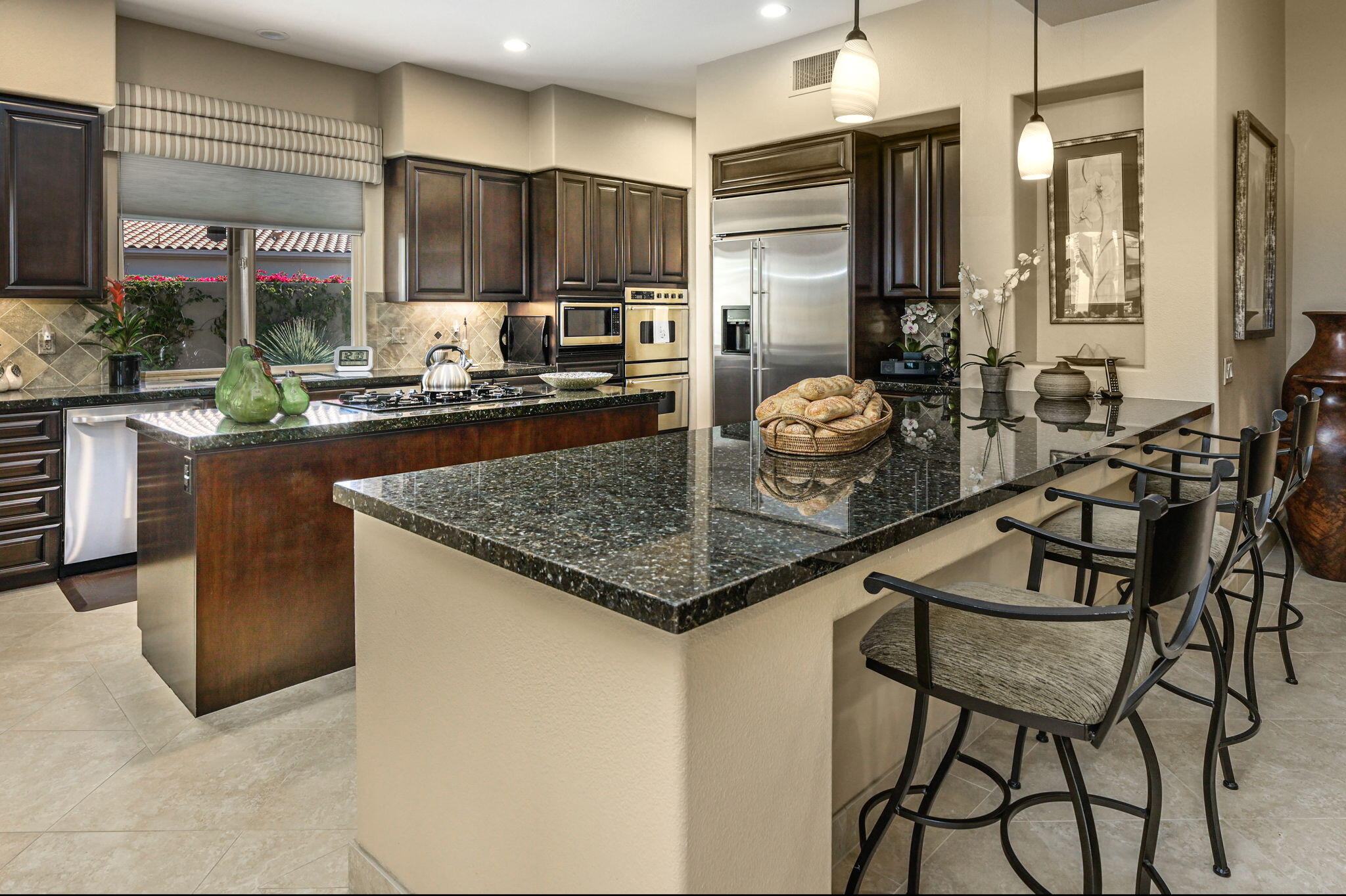 328 Tomahawk Drive Palm Desert, CA 92211 - Photo 10 of 56 a kitchen with stainless steel appliances granite countertop a table chairs and a refrigerator