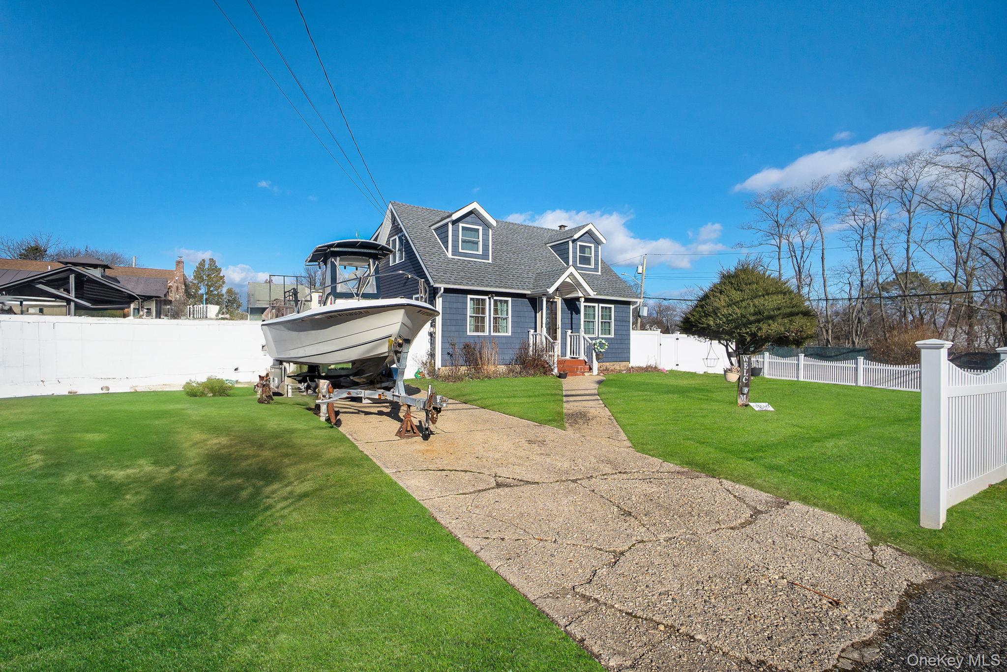 91 Cedar Road Amityville, NY 11701 - Photo 3 of 30 a front view of a house with a yard fire pit and chairs