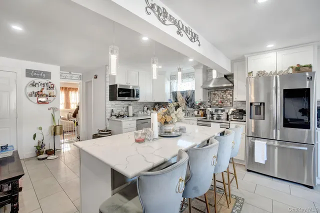 a kitchen with stainless steel appliances kitchen island granite countertop a refrigerator a stove a sink a dining table and chairs with wooden floor