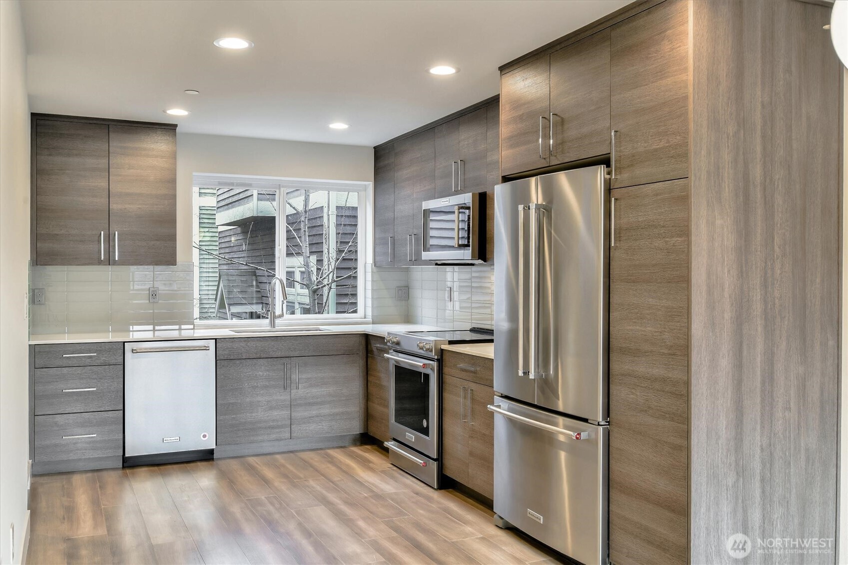 1919 24th Avenue South, Unit D Seattle, WA 98144 - Photo 7 of 35 a kitchen with stainless steel appliances granite countertop a refrigerator a sink a stove and white cabinets with wooden floor
