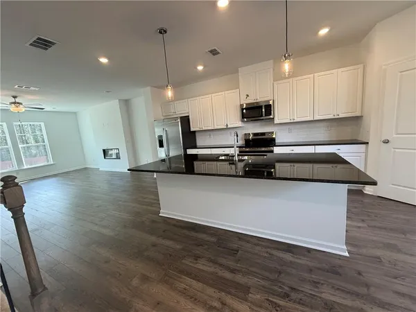 a kitchen with stainless steel appliances granite countertop a refrigerator a sink dishwasher a stove and white countertops with wooden floor