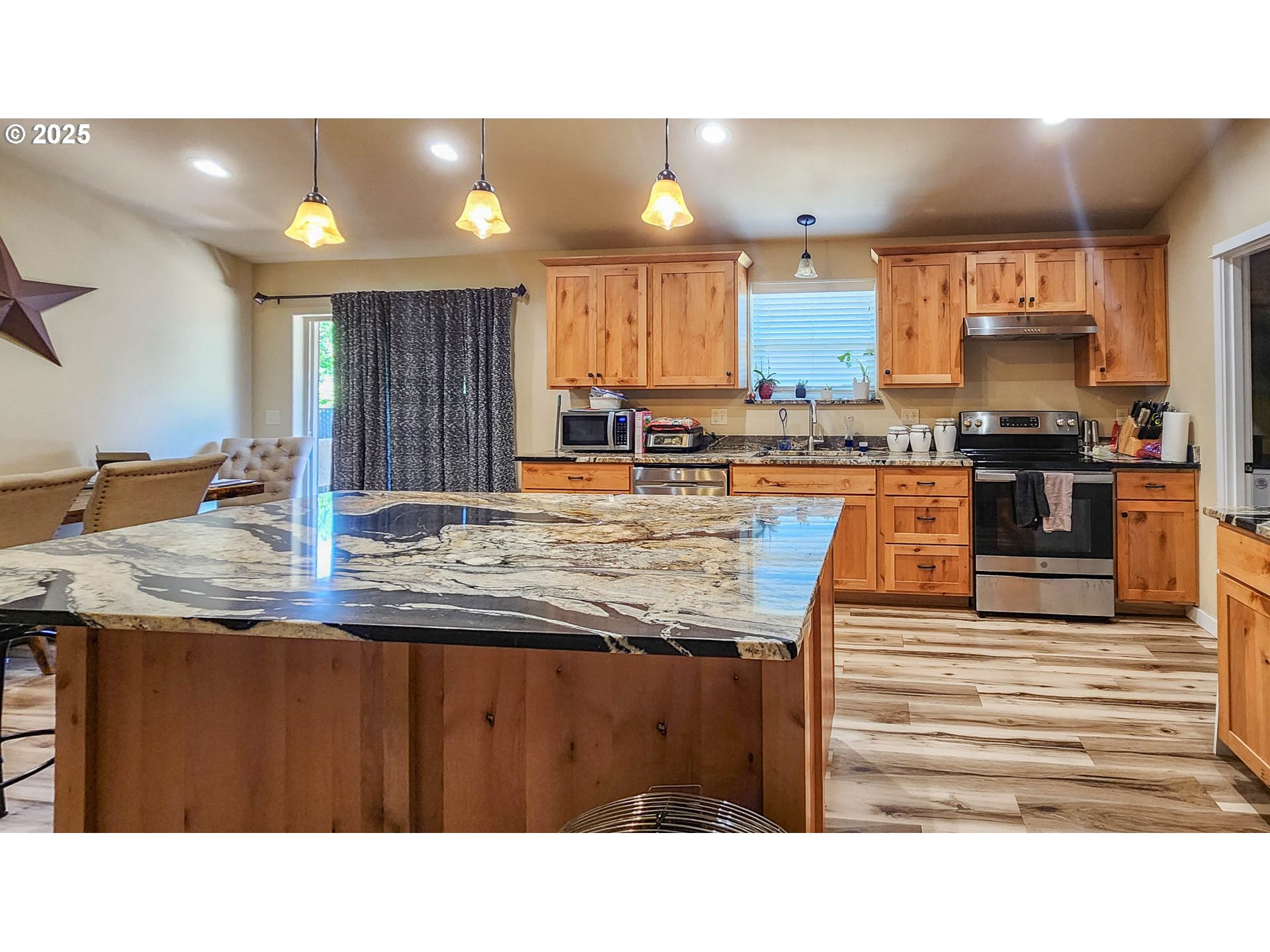 5135 Southwest Grange Road Roseburg, OR 97471 - Photo 6 of 27 a kitchen with stainless steel appliances kitchen island granite countertop a stove a sink and a microwave