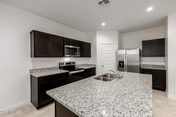 a kitchen with stainless steel appliances granite countertop a sink stove microwave and refrigerator