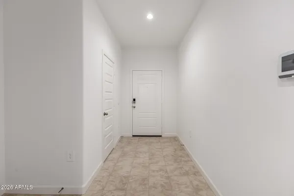 an empty room with kitchen view and a refrigerator