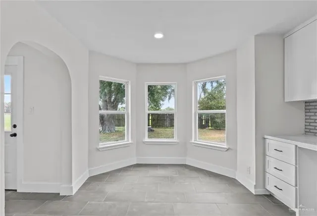 a view of an empty room with a window and cabinet