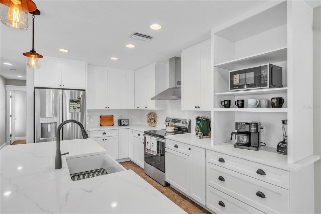302 67th Street Holmes Beach, FL 34217 - Photo 13 of 38 a kitchen with stainless steel appliances a sink a stove a refrigerator and cabinets