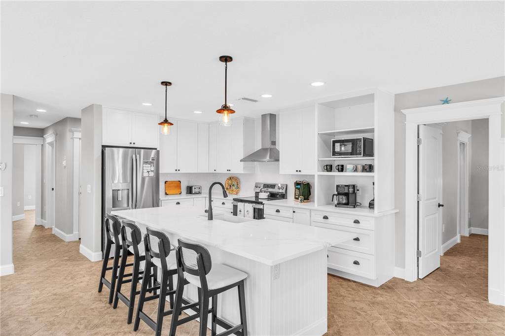 302 67th Street Holmes Beach, FL 34217 - Photo 15 of 38 a kitchen with stainless steel appliances kitchen island granite countertop a table chairs and a refrigerator