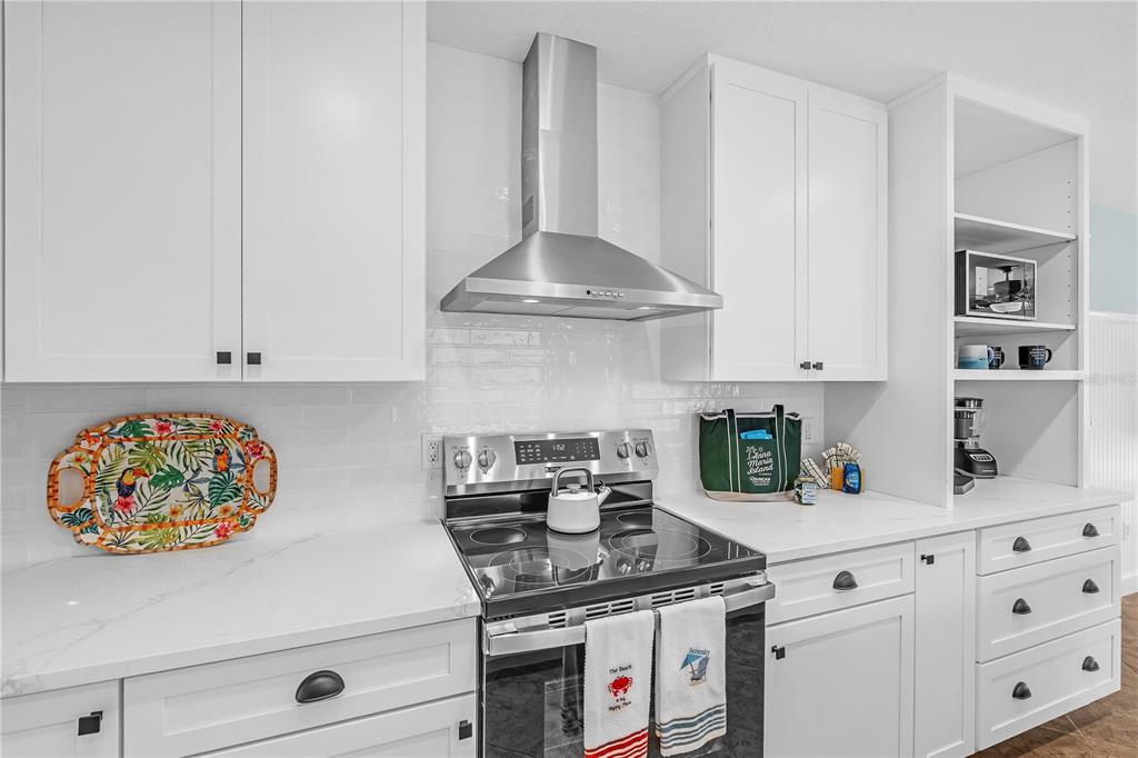 302 67th Street Holmes Beach, FL 34217 - Photo 7 of 38 a kitchen with stainless steel appliances granite countertop a white stove top oven and white cabinets