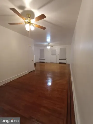 an empty room with wooden floor fan and window