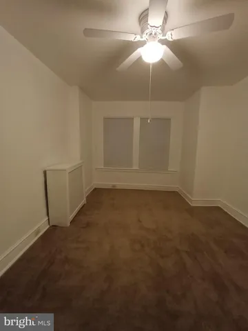 an empty room with a fan & a window