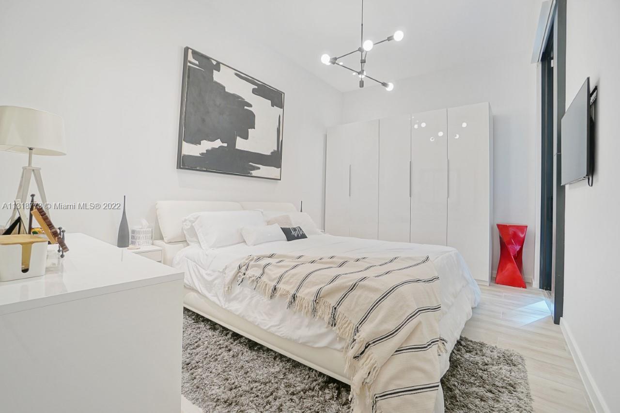 3156 Southwest 27th Avenue, Unit 101 Miami, FL 33133 - Photo 16 of 29 a bedroom with a bed and a chandelier
