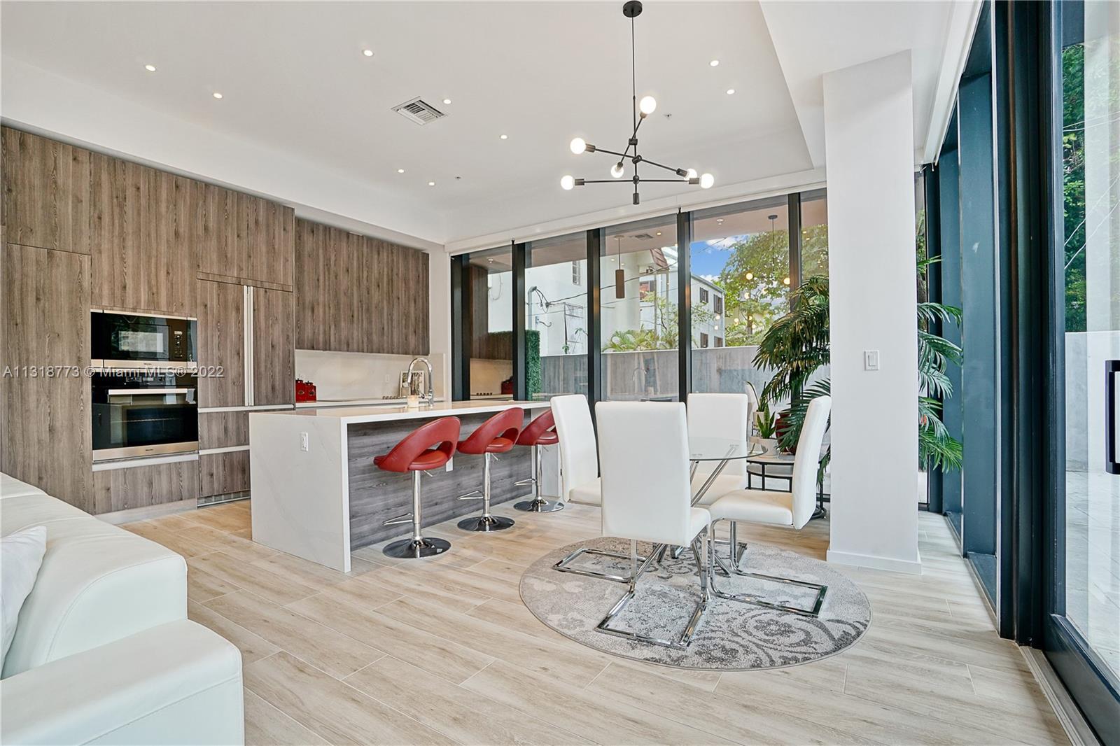 3156 Southwest 27th Avenue, Unit 101 Miami, FL 33133 - Photo 3 of 29 a living room with furniture a dining table and a floor to ceiling window