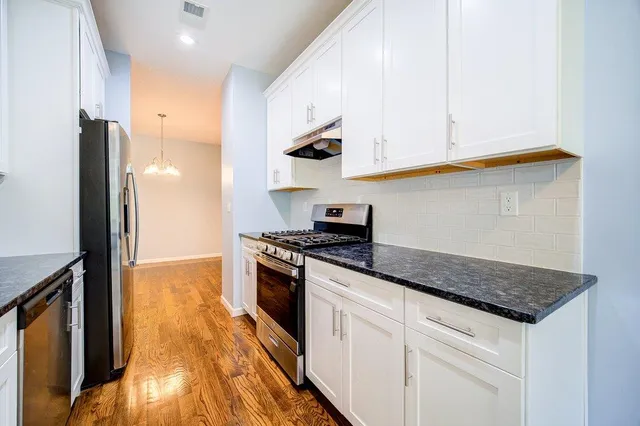 a kitchen with stainless steel appliances granite countertop a stove a sink and a refrigerator