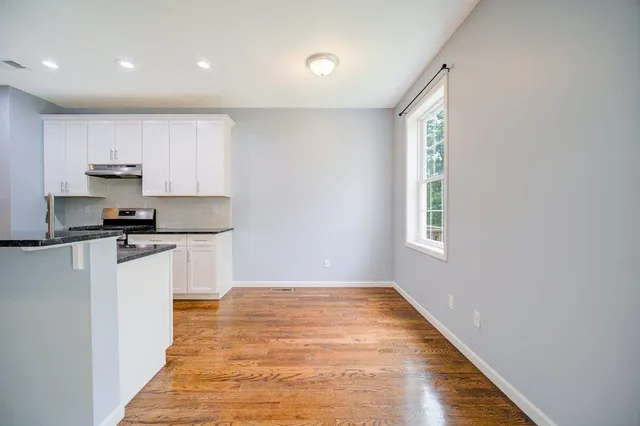 a kitchen with white cabinets a sink a window and a refrigerator