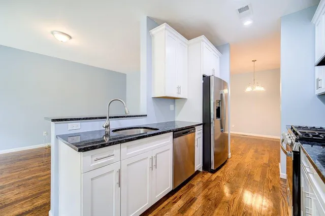 a kitchen with stainless steel appliances granite countertop a sink and wooden cabinets