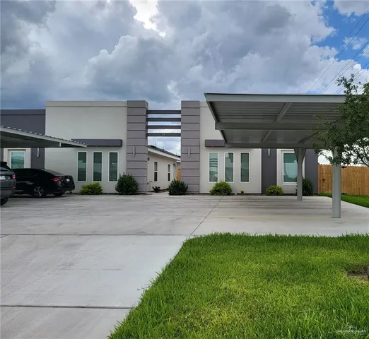 a front view of a house with a yard and potted plants