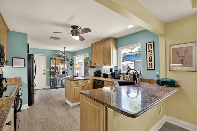 a kitchen with stainless steel appliances granite countertop a refrigerator a stove top oven a sink dishwasher a dining table and chairs with wooden floor