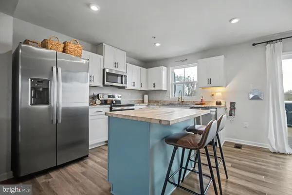a kitchen with stainless steel appliances granite countertop a refrigerator a sink dishwasher a stove with wooden cabinets and wooden floor