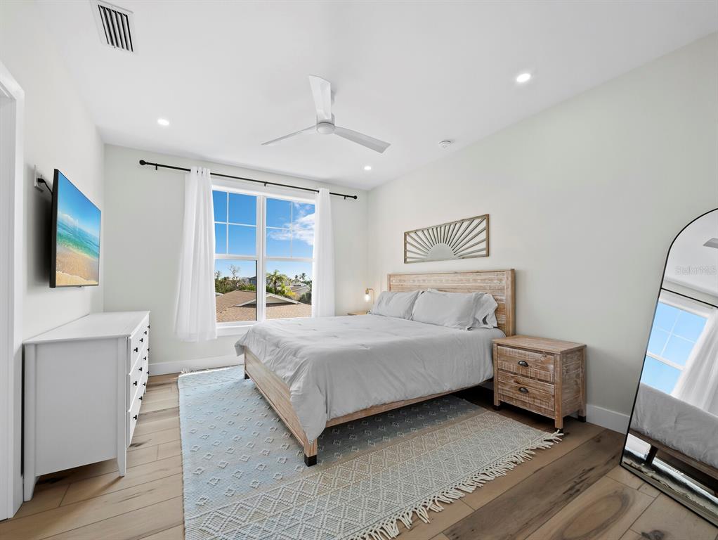 630 Companion Way Longboat Key, FL 34228 - Photo 27 of 66 a bedroom with a bed a couch and a flat tv screen on dresser