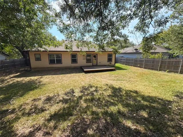 a backyard of a house with large trees and a wooden fence