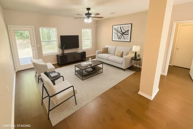 a living room with furniture a flat screen tv and a window