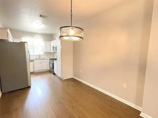 a view of a kitchen with a refrigerator a stove top oven a wooden floor