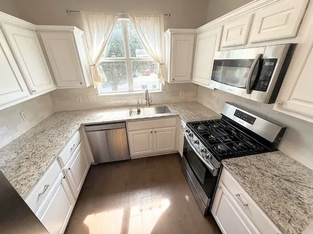 a kitchen with stainless steel appliances granite countertop a stove a sink and a microwave
