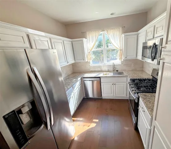 a kitchen with stainless steel appliances granite countertop a sink stove and refrigerator