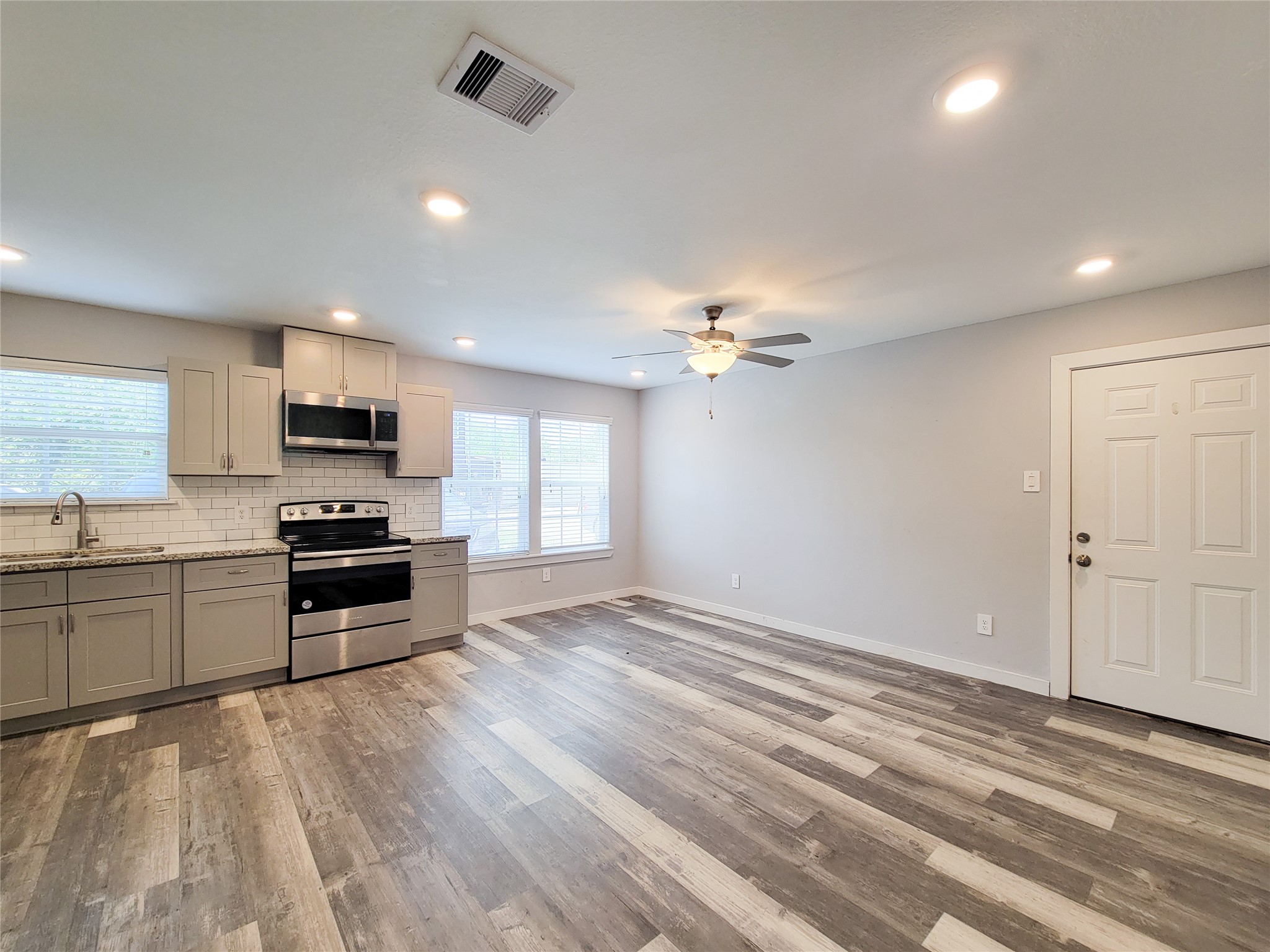 7202 Sandle Street, Unit A Houston, TX 77088 - Photo 7 of 29 a kitchen with granite countertop a stove top oven a sink dishwasher and a refrigerator with wooden floor