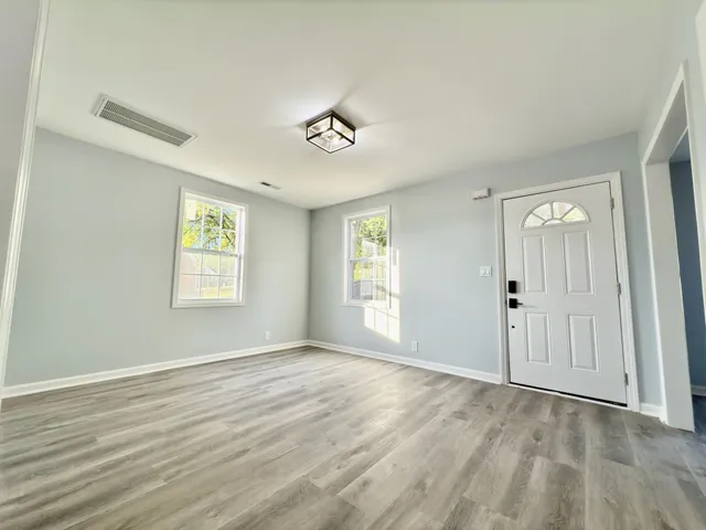 a view of an empty room with wooden floor and a window