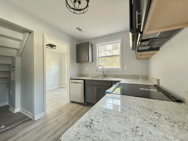 a kitchen with granite countertop a sink a stove and cabinets