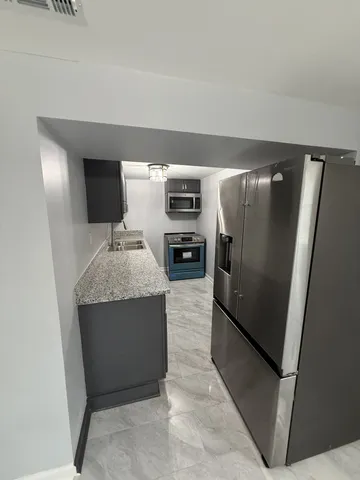 a kitchen with stainless steel appliances granite countertop a refrigerator and a sink