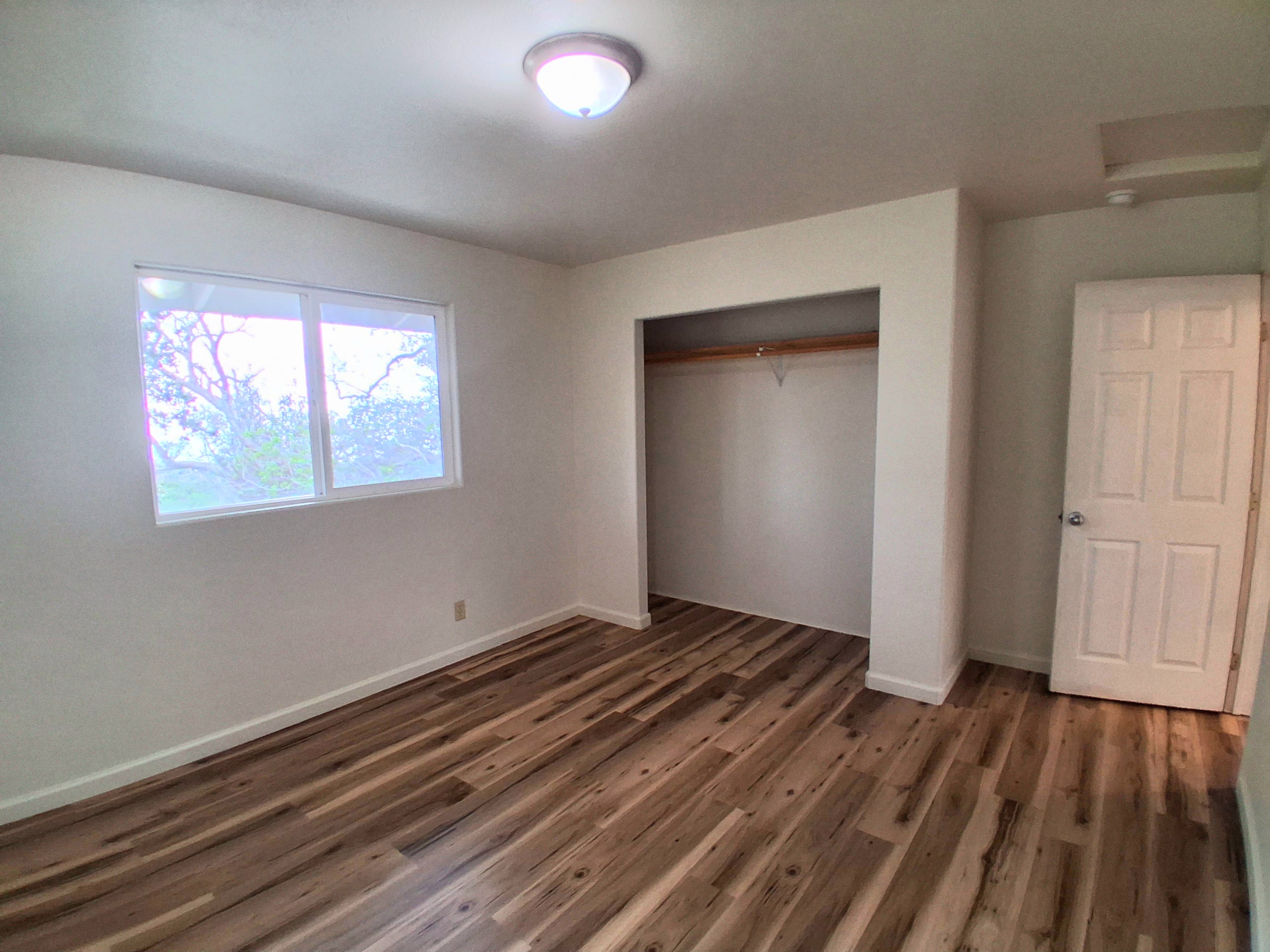 92-8221 Reef Parkway Ocean View, HI 96704 - Photo 14 of 20 a view of an empty room with wooden floor and a window